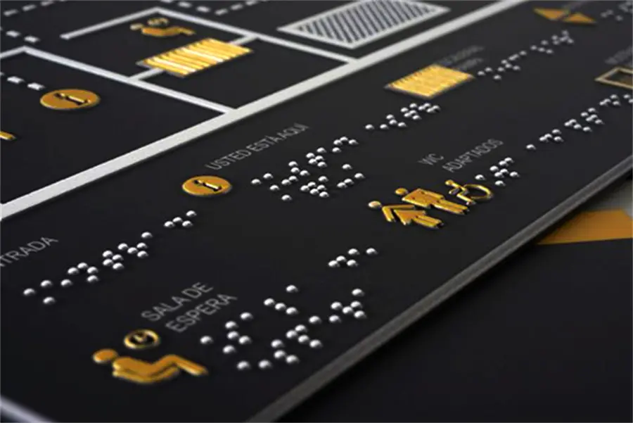 Taktiler Etagenplan mit Braille und goldenen Piktogrammen auf Schwarz