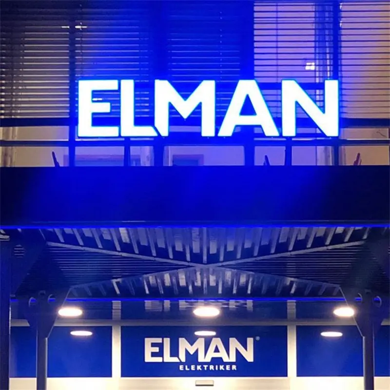 Blaue Leuchtbuchstaben von Elman, beleuchtet über dem Eingang eines Geschäftsgebäudes
